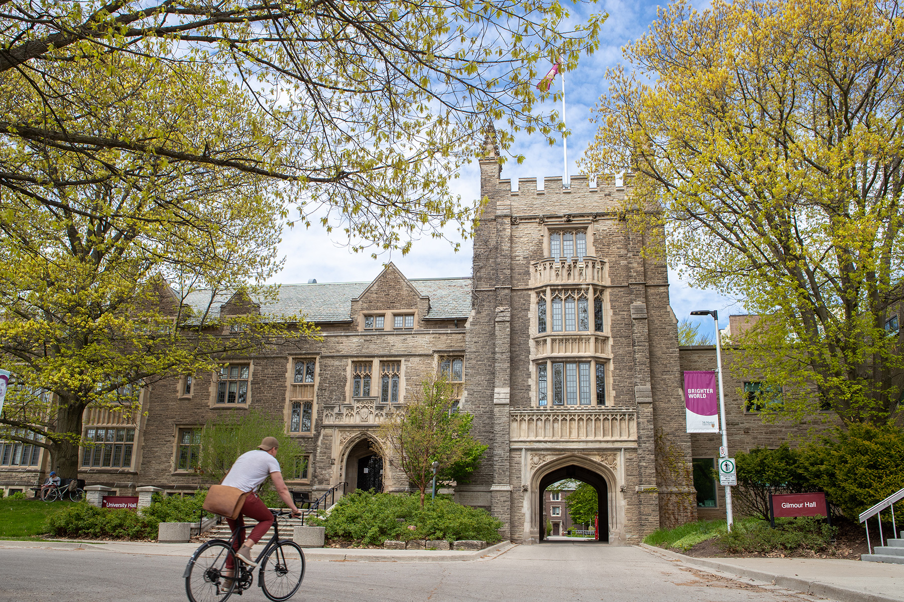 Cyclist biking toward University Hall Arch on campus.