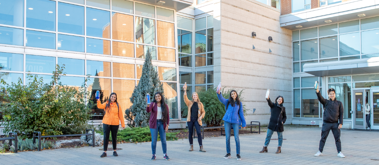 Students outside on campus holding up refillable water bottles